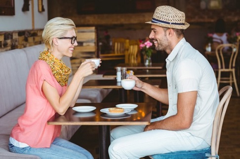 Cute couple on a date talking over a cup of coffee at the cafe